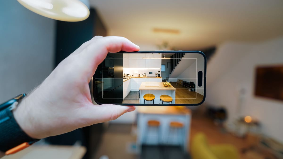 A hand holding a phone that frames a modern apartment kitchen
